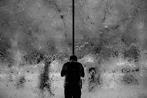 people man standing on glass wall with pouring water black-and-white