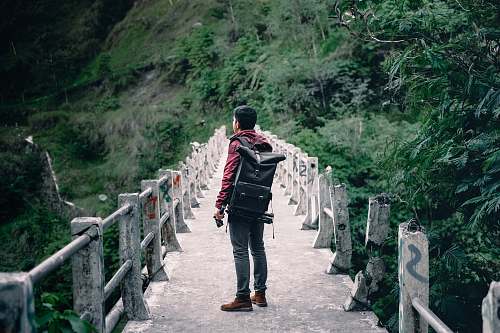 person man standing on gray concrete bridge taken at daytime people