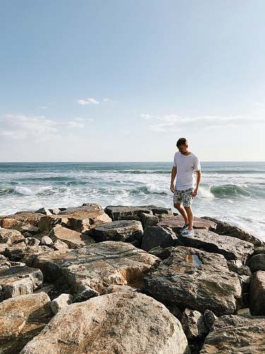 people man standing on rocks near body of water person