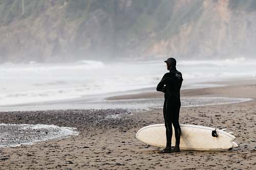people man standing on shoreline with surfboard person