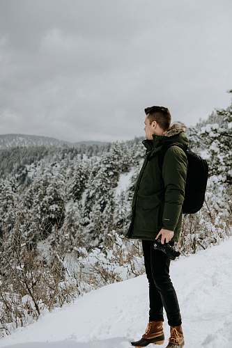 people man standing on snow looking at trees under cloudy sky person