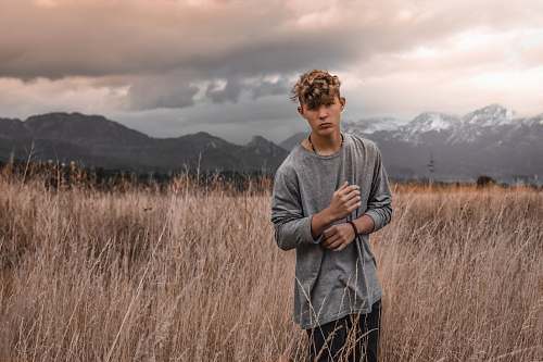 people man standing on the ground surrounded by grass and holding his sleeve person