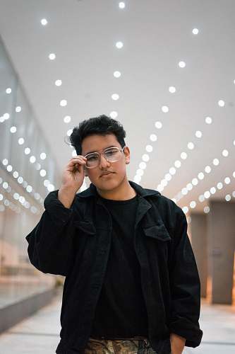 people man standing while holding his eyeglasses inside room person