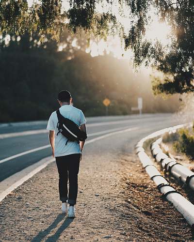 people man walking beside road during orange sunset person