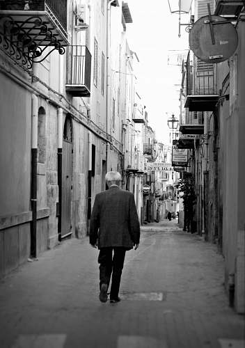 people man walking between of buildings black-and-white