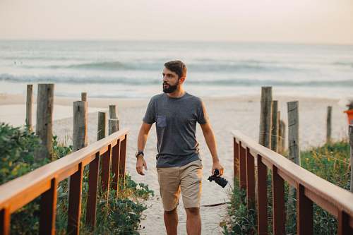 people man walking holding camera near shoreline person