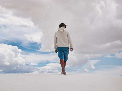 person man walking on white surface under white clouds and blue sky during daytime people