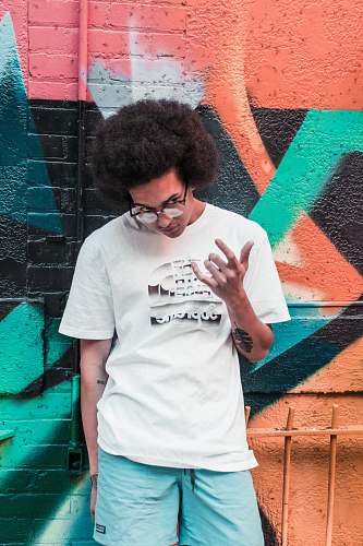 people man wearing black framed eyeglasses standing near printed wall person