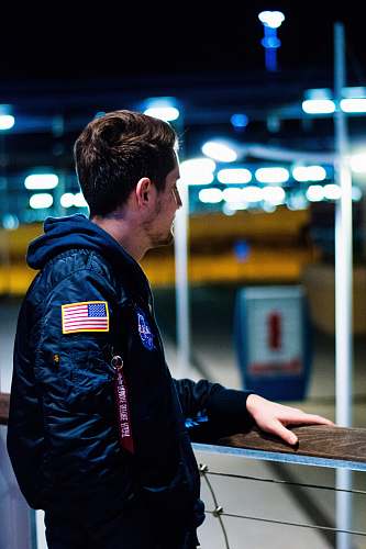 people man wearing blue jacket standing near the fence person