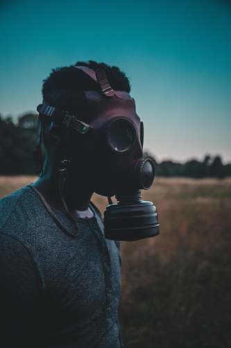 people man wearing brown gas mask standing on brown field person