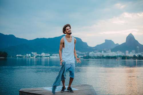 person man wearing gray tank top near the body of water people