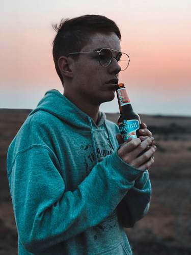 people man wearing hoodie holding a bottle of beer person