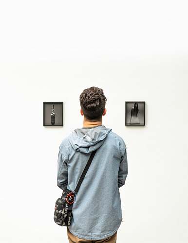 people man wearing hoodie looking at artworks person