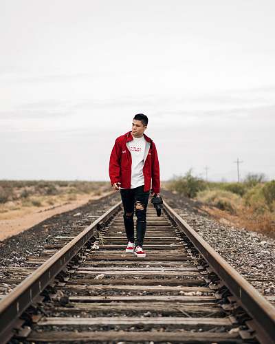 people man wearing jacket waking on train rail person