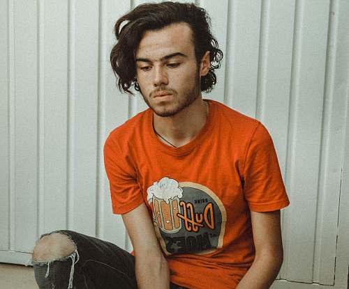people man wearing orange crew-neck t-shirt near white wall person
