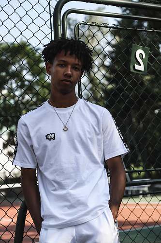 people man wearing white t-shirt beside gray wire fence person