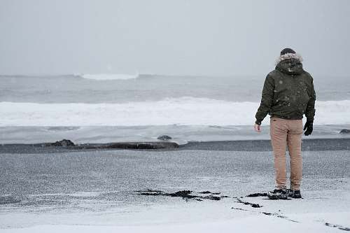 people person in grey jacket and brown standing standing at the shore person