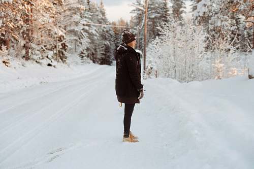 people person on snowy road surrounded by trees person