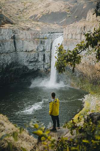 people person standing near waterfall during daytime person