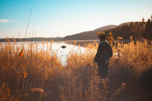 people person standing on grass field near lake and mountain range person