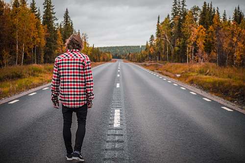 person person standing on middle of blacktop road during daytime people