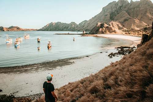 people person standing on shore near boats during daytime person
