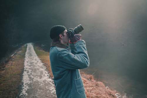 people photo of man holding DLSR camera looking up and taking a photo person