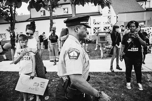 person police men walking near person in black shirt taking video black-and-white