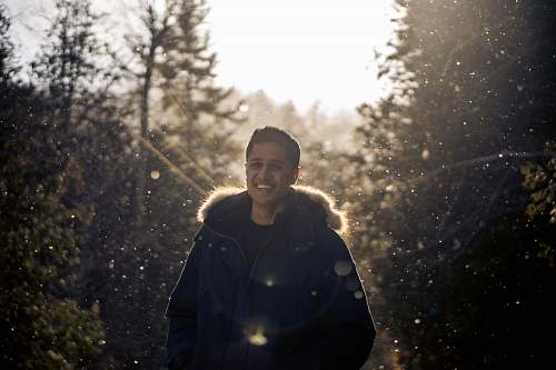 person selective focus photo of man standing between pine trees people