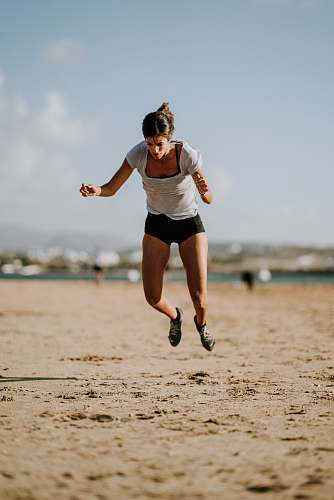 people selective focus photo of woman jumping on seashore person