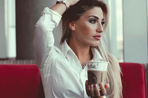 people selective focus photo of woman taking post while holding white disposable cup person