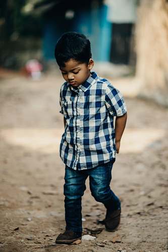 people selective focus photography of boy in blue and white checked button-up shirt looking down person