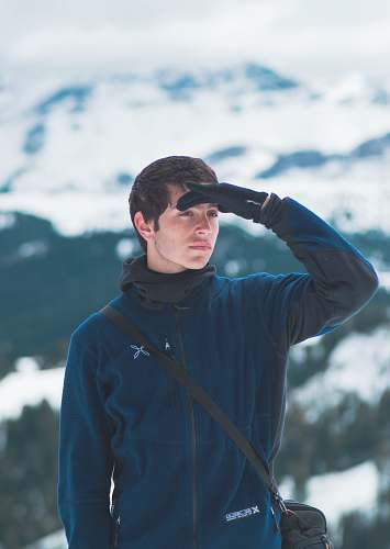 people selective focus photography of man's right hand on forehead standing on snow capped mountain during daytime person