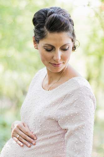 people selective focus photography pregnant woman looking down white holding her tummy person