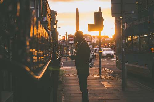 people silhouette photography of man standing in front of building person