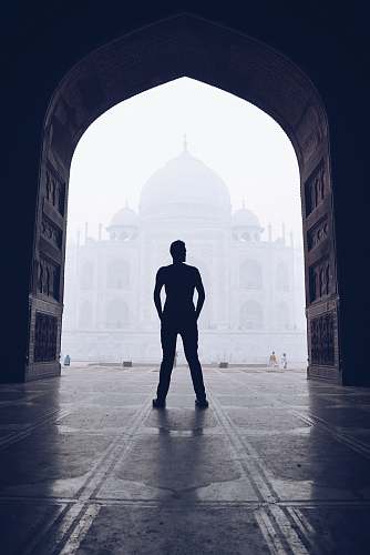person silhouette photography of man standing near door in front of mosque people
