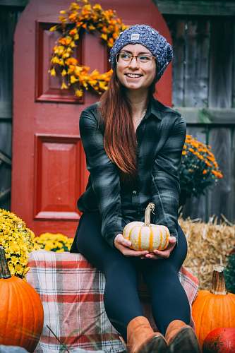 people smiling woman sitting and holding orange pumpkin person
