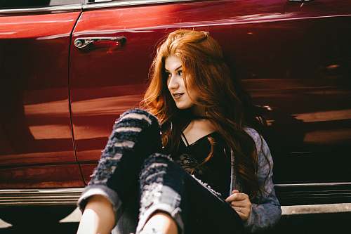 people smiling woman sitting beside red car woman