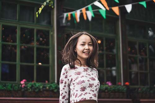 people smiling woman standing under multicolored buntings during daytime person