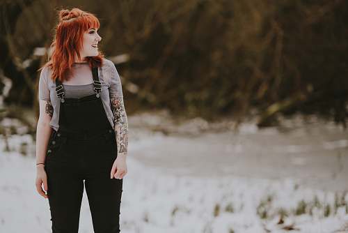 people smiling woman wearing black overalls standing on white ground at daytime person