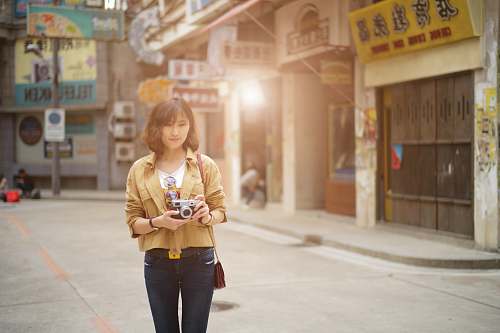 people standing woman holding camera near stores person