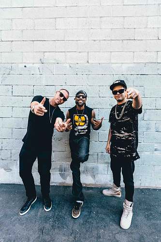 people three man standing behind gray concrete wall at daytime person
