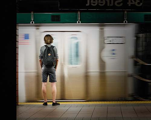 people time lapse photography of man standing in front of train person