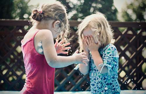 person two children playing water during daytime shallow focus photography people