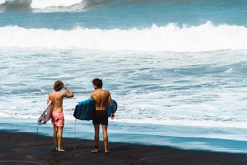 people two men carrying surfboards on shoreline person