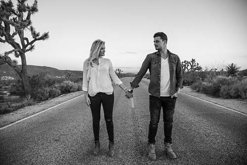 people woman and man standing on concrete road black-and-white