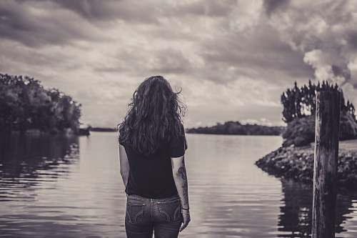 people woman facing body of water grey