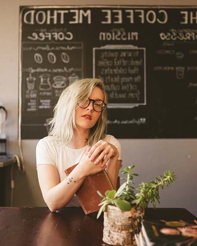 people woman holding book by the table plant