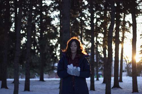 people woman holding snow near trees during sunset person