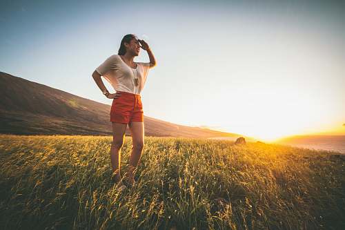 people woman in beige batwing sleeved shirt and red shorts standing on grass field person